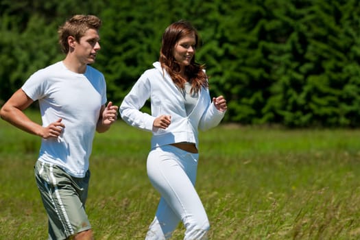 Young couple jogging outdoors in spring nature on sunny day