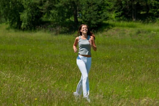 Young smiling woman jogging in the nature, shallow DOF