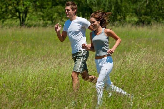 Young couple jogging outdoors in spring nature on sunny day