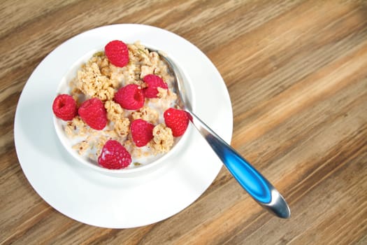 Fresh morning bowl of granola and raspberries with milk