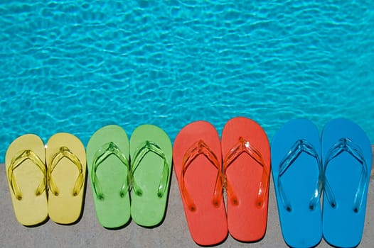 Colored flipflops of a family of four by the swimming pool