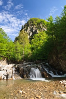 a beautiful waterfall between the mountains and trees