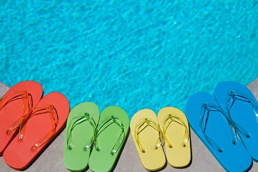 Colored flipflops of a family of four by the swimming pool