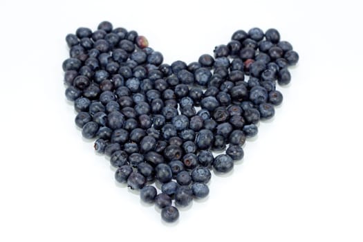 Blue purple fruit berry in the shape of love on a reflective white background.