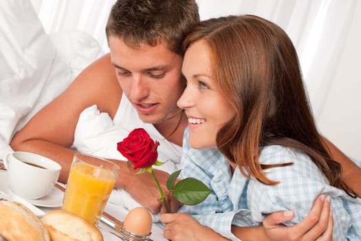 Happy man and woman having luxury hotel breakfast in bed together