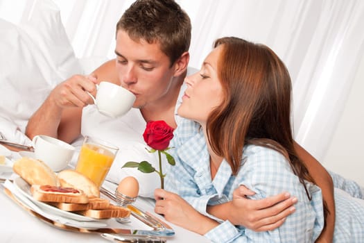 Happy man and woman having luxury hotel breakfast in bed together