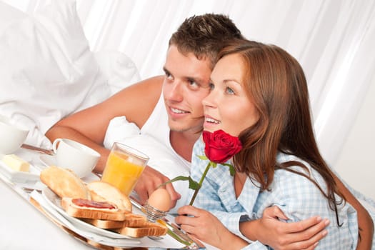 Happy man and woman having luxury hotel breakfast in bed together