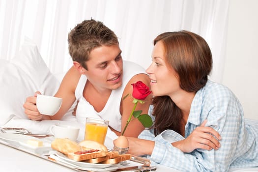 Happy man and woman having luxury hotel breakfast in bed together