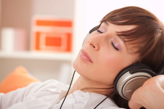 woman listening music in earphones at home