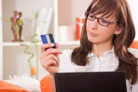 woman with credit card and laptop thinking about internet shopping