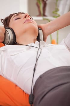 woman in business suit relaxing at home and hearing music in earphones