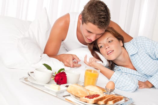 Happy man and woman having luxury hotel breakfast in bed together