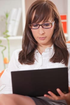woman in business shirt with small laptop computer at home