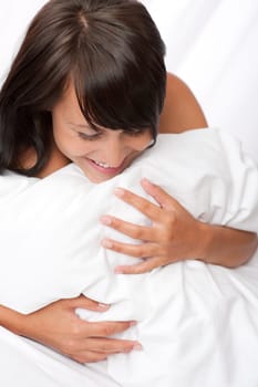 Smiling young woman in white bed, shallow DOF