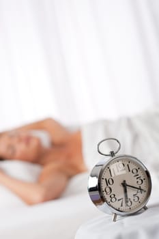 Silver alarm clock, woman in background, shallow DOF