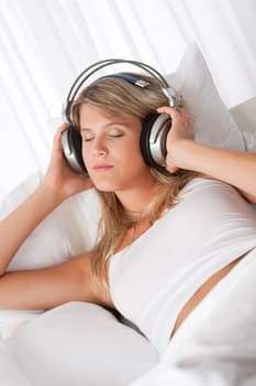 Blond woman with headphones listening to music with closed eyes