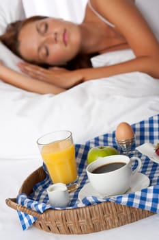 Young woman having home made breakfast in bed, sleeping