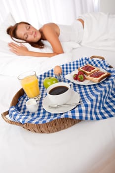 Young woman having home made breakfast in bed, sleeping