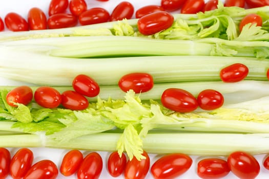 Fresh long green vegetable and small round red fruit mix on white.