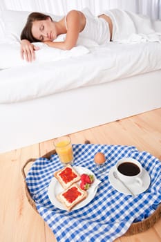 Woman having homemade breakfast lying in bed and sleeping