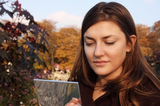 girl doing makeup in an autumn park