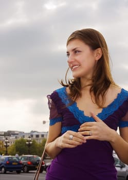 Happy girl in summer dress standing against the street traffic