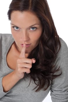 Beautiful woman expressing silence, finger on lips, on white background