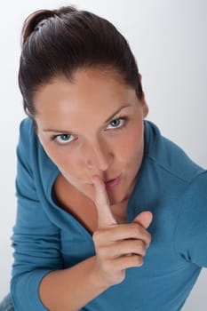 Young woman with finger on lips on white background, silence