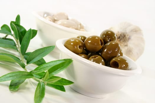 Olives in a white bowl and an olive branch