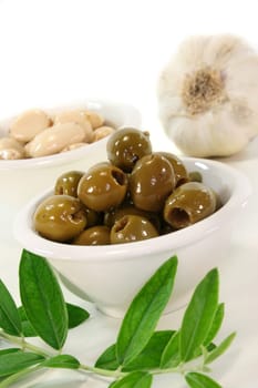 Olives in a white bowl and an olive branch