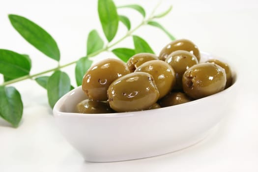 Olives in a white bowl and an olive branch