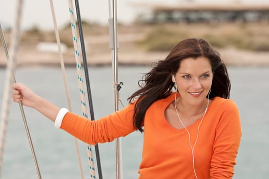 Attractive woman standing on sailing boat holding rope