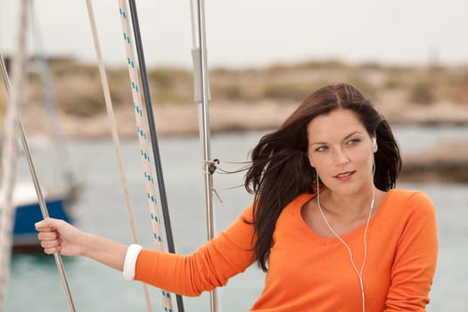 Attractive woman standing on sailing boat holding rope