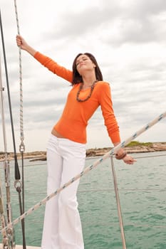 Attractive woman sailing on luxury yacht holding rope