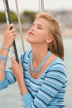 Blond young woman on sailing boat holding rope