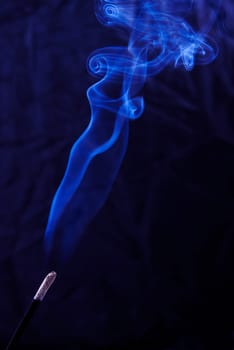 Abstract incense blue smoke against black background