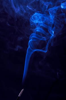 Abstract incense blue smoke against black background