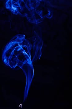Abstract incense blue smoke against black background