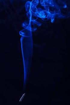 Abstract incense blue smoke against black background