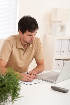 Successful modern businessman with laptop sitting at the office