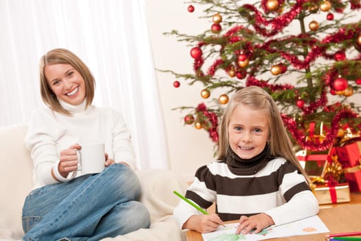 Happy blond woman with child on Christmas in front of tree