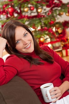 Brown hair woman relaxing with cup of coffee in front of Christmas tree