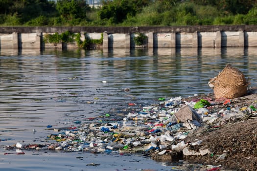 Water pollution - heavily polluted river inlet with various garbage along shore and floating on water. Manila, Philippines.