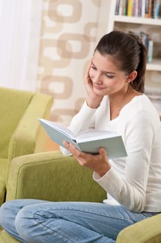 Students - Happy teenager with book sitting on armchair in lounge
