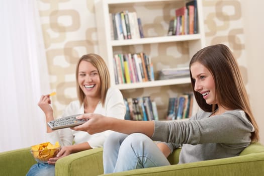 Students - Two female teenager watching television and eating crisps in modern lounge