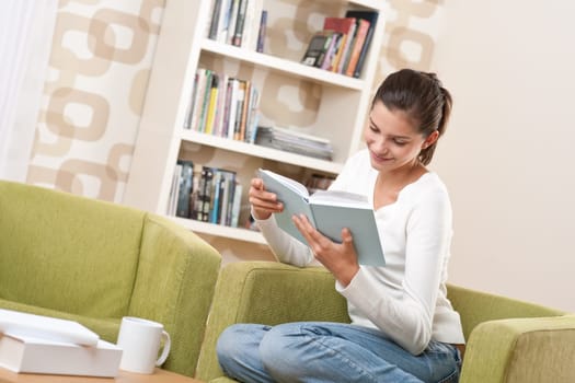 Students - Happy teenager with book sitting on armchair in lounge