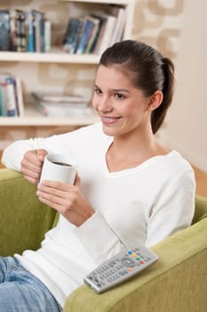 Students - Happy female teenager having drink watching television in living room