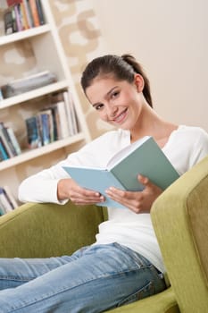 Students - Happy teenager with book sitting on armchair in lounge