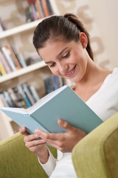 Students - Happy teenager with book sitting on armchair in lounge