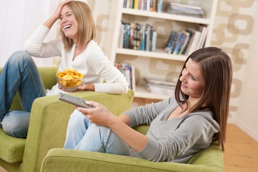 Students - Two smiling female teenager watching television in modern living room
